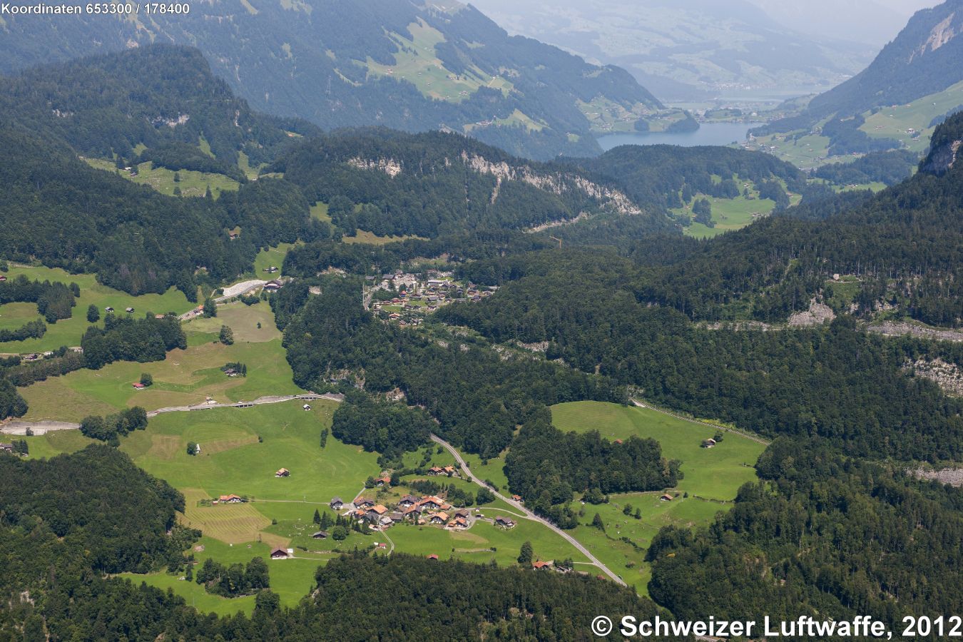 Dorf im Vordergrund. Brünigen; Bildmitte: Brünig Passhöhe; im Hintergrund Lungerensee, ganz hinten: Sarnersee